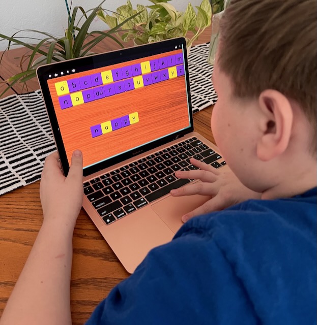 Child using TacTilesPlus digital tiles on a laptop